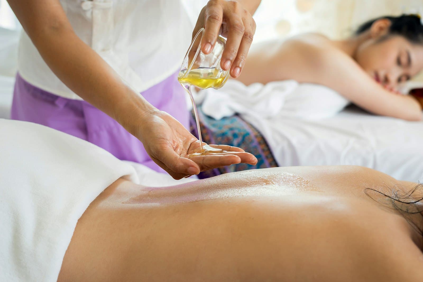Spa therapist pouring warm oil during a holistic massage treatment